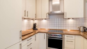 Una cocina con armarios blancos, horno de acero inoxidable y encimera de madera.