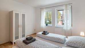 Una habitación con dos camas, un armario, una ventana con vistas y una lámpara.