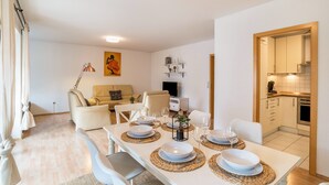 Un comedor con una mesa blanca dispuesta para cuatro personas, rodeada de sillas blancas.