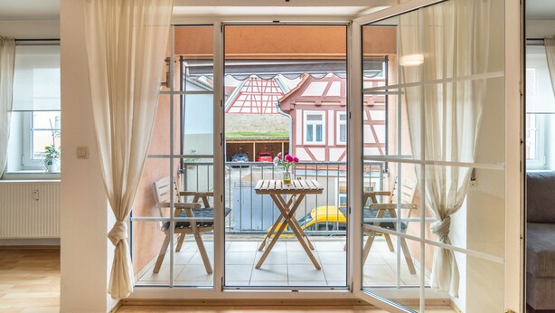 Una habitación con un amplio ventanal corredero que da a un espacio exterior con una mesa y sillas.