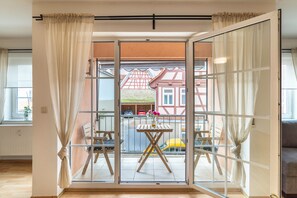 Una habitación con un amplio ventanal corredero que da a un espacio exterior con una mesa y sillas.