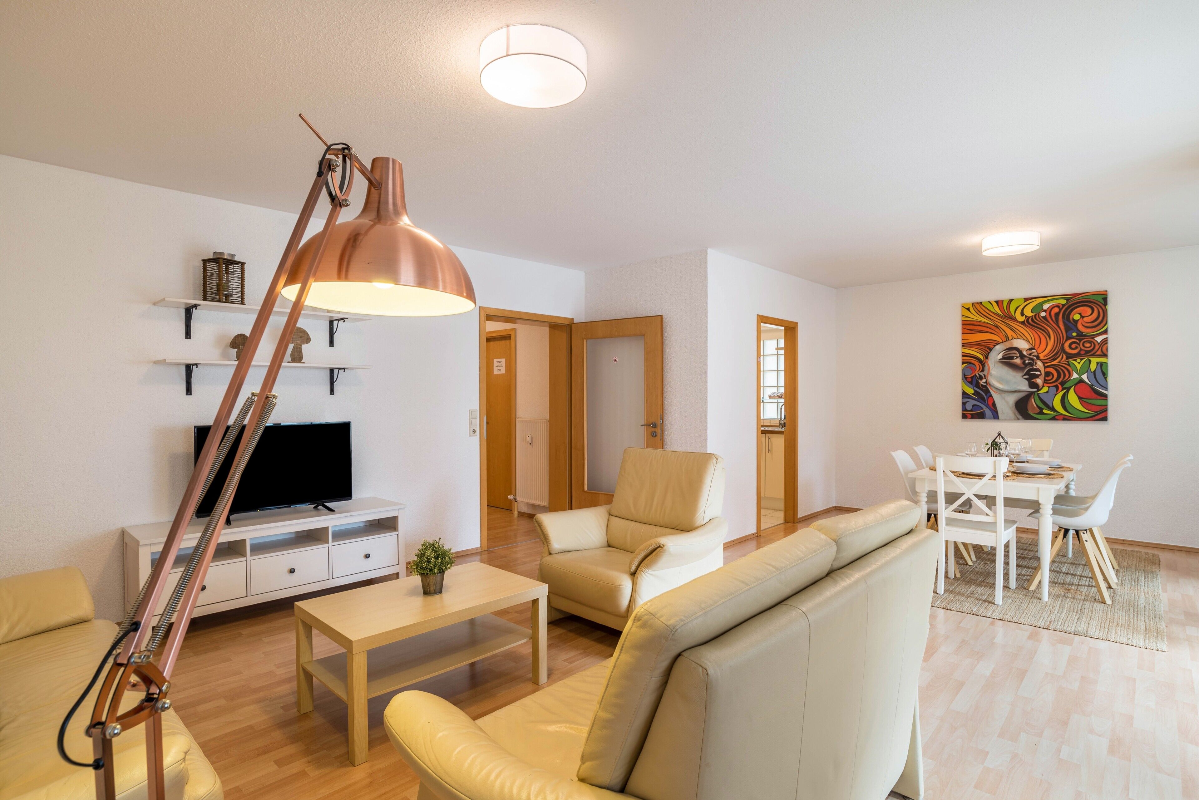 Ett modernt vardagsrum med en soffa, ett soffbord, en lampa, en tv och en matplats.