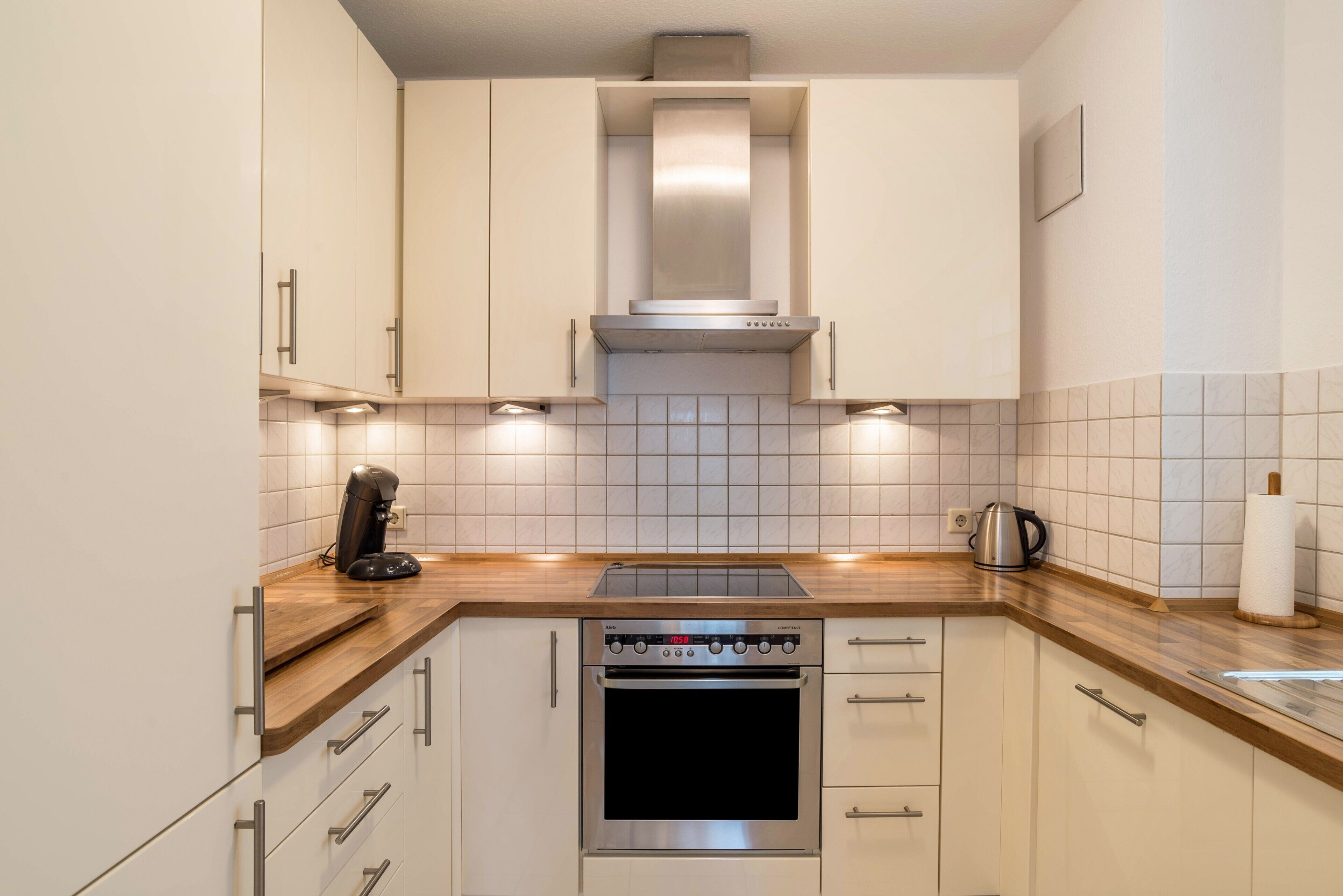 Eine Küche mit weißen Schränken, einem Edelstahlbackofen und einer Holz Arbeitsplatte.