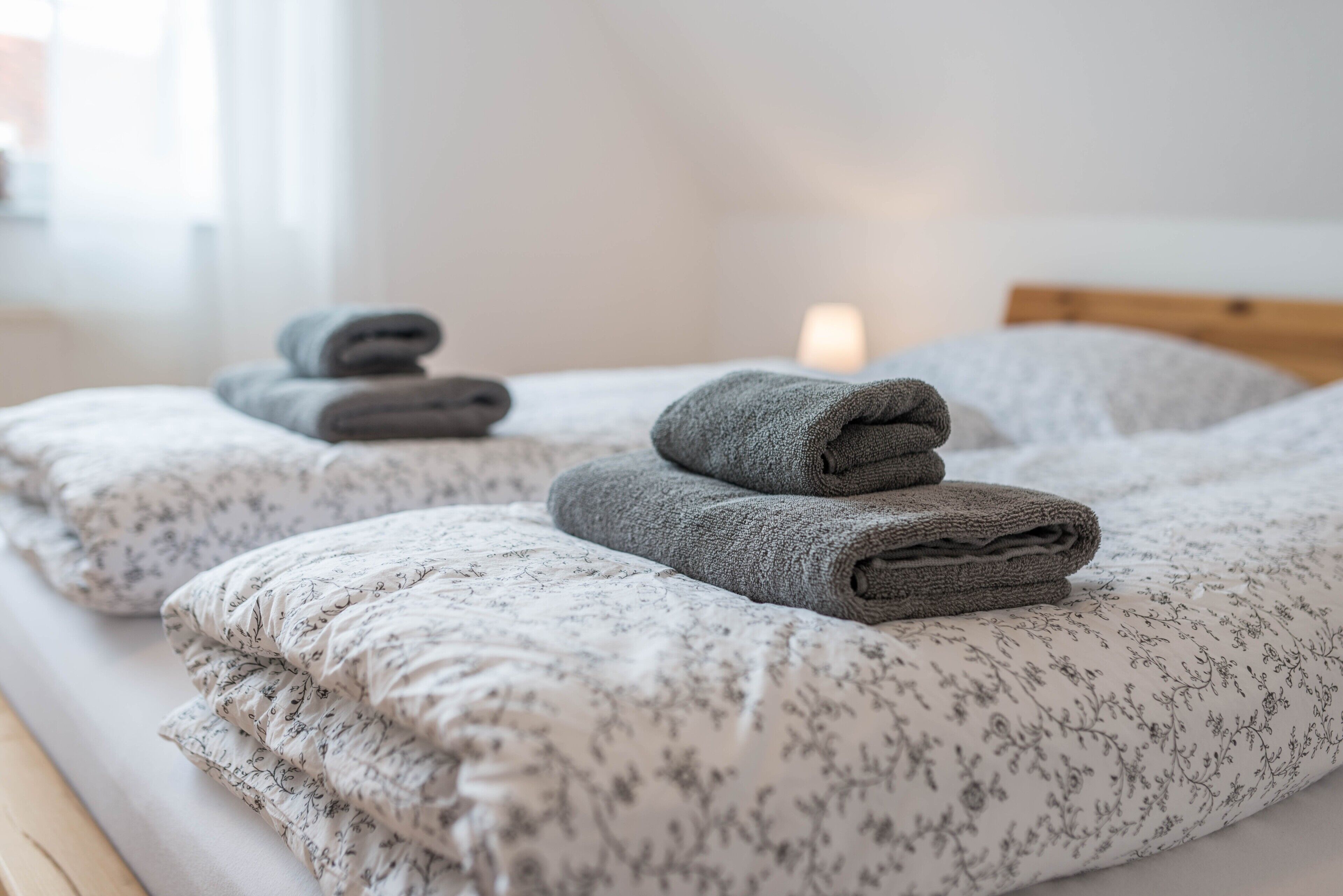 A neatly made bed with floral-patterned bedding and folded towels.