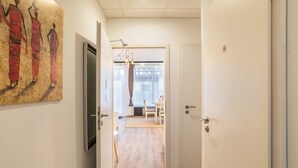 En gang med en dør, der fører til et rum med et mønstret gulv og et vindue med gardiner.