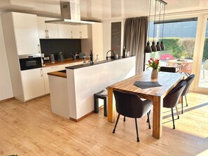 Una cocina moderna con armarios blancos, una isla de madera y un comedor con mesa de madera y sillas negras.