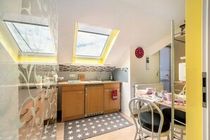 Une cuisine compacte dotée de fenêtres de toit, un coin repas avec une chaise et un radiateur apparent.