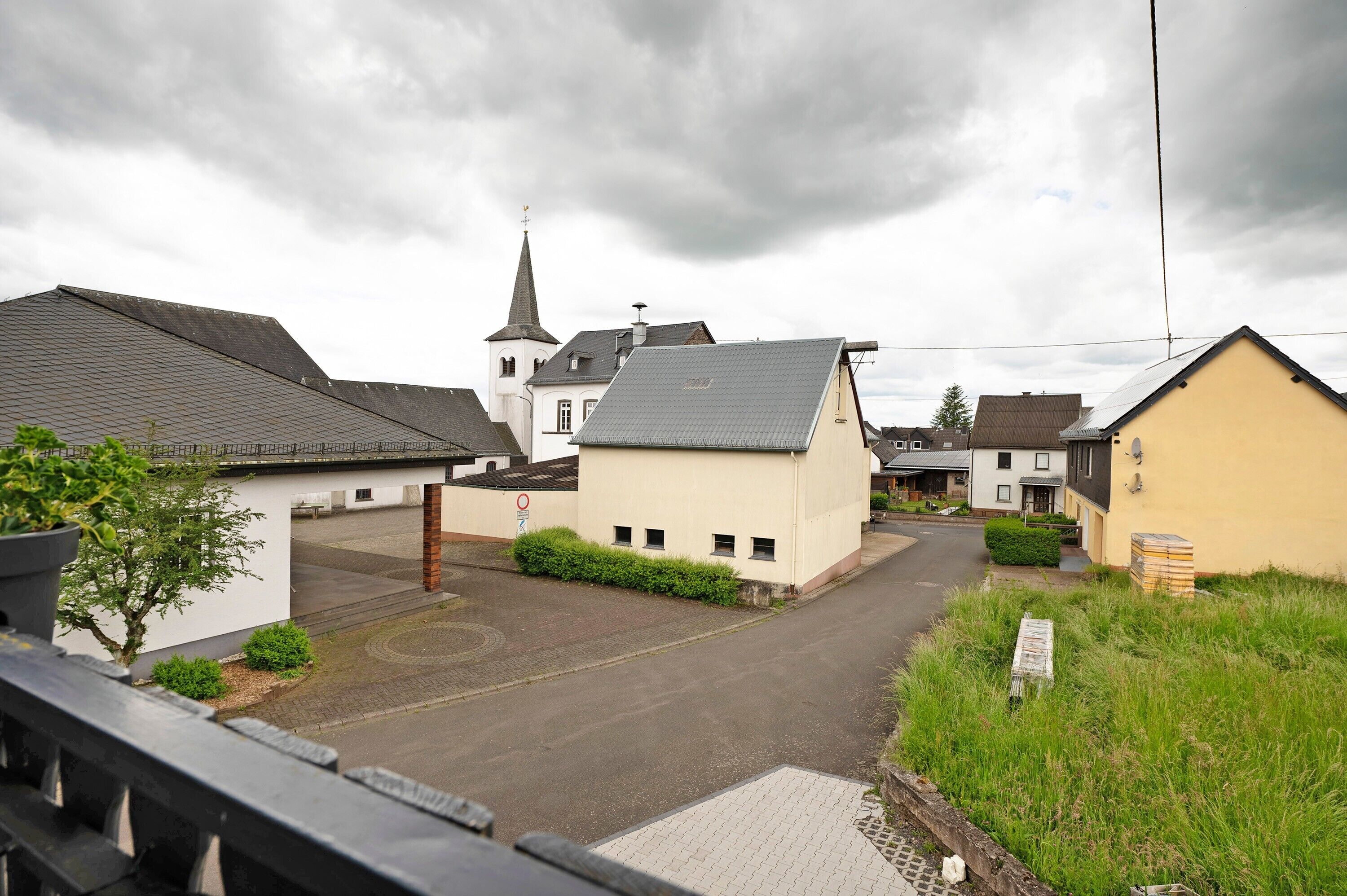 En bostadsgata med hus, en kyrka och en asfalterad väg.