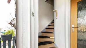 A spiral staircase with black carpeted steps and a wooden finish, leading to an upper floor. - Picco 1: Modern Comfort Apartment with Balcony near Calmont Summit (Beuren)