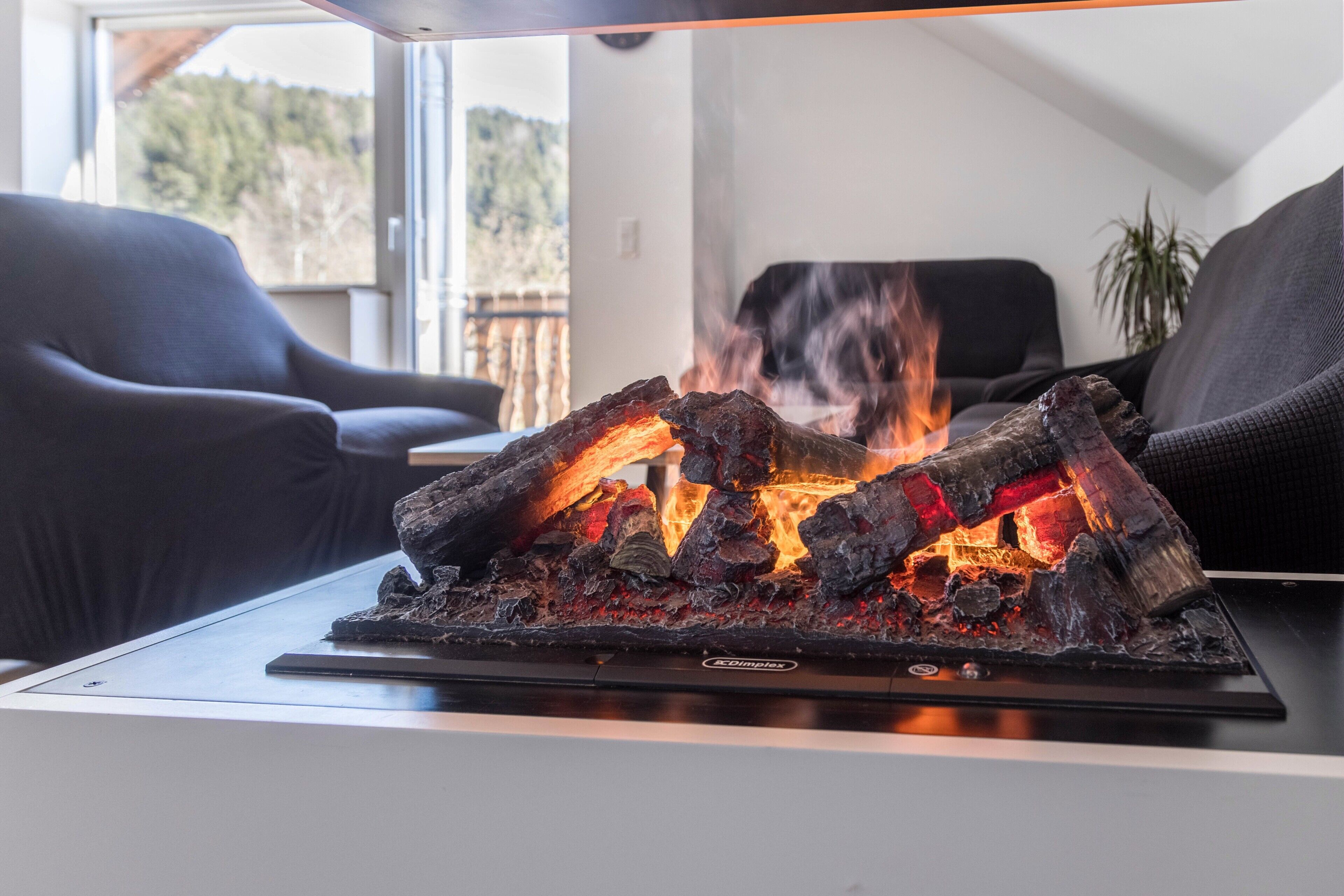 A modern living room with a fireplace, a sofa, and a view of the outdoors.