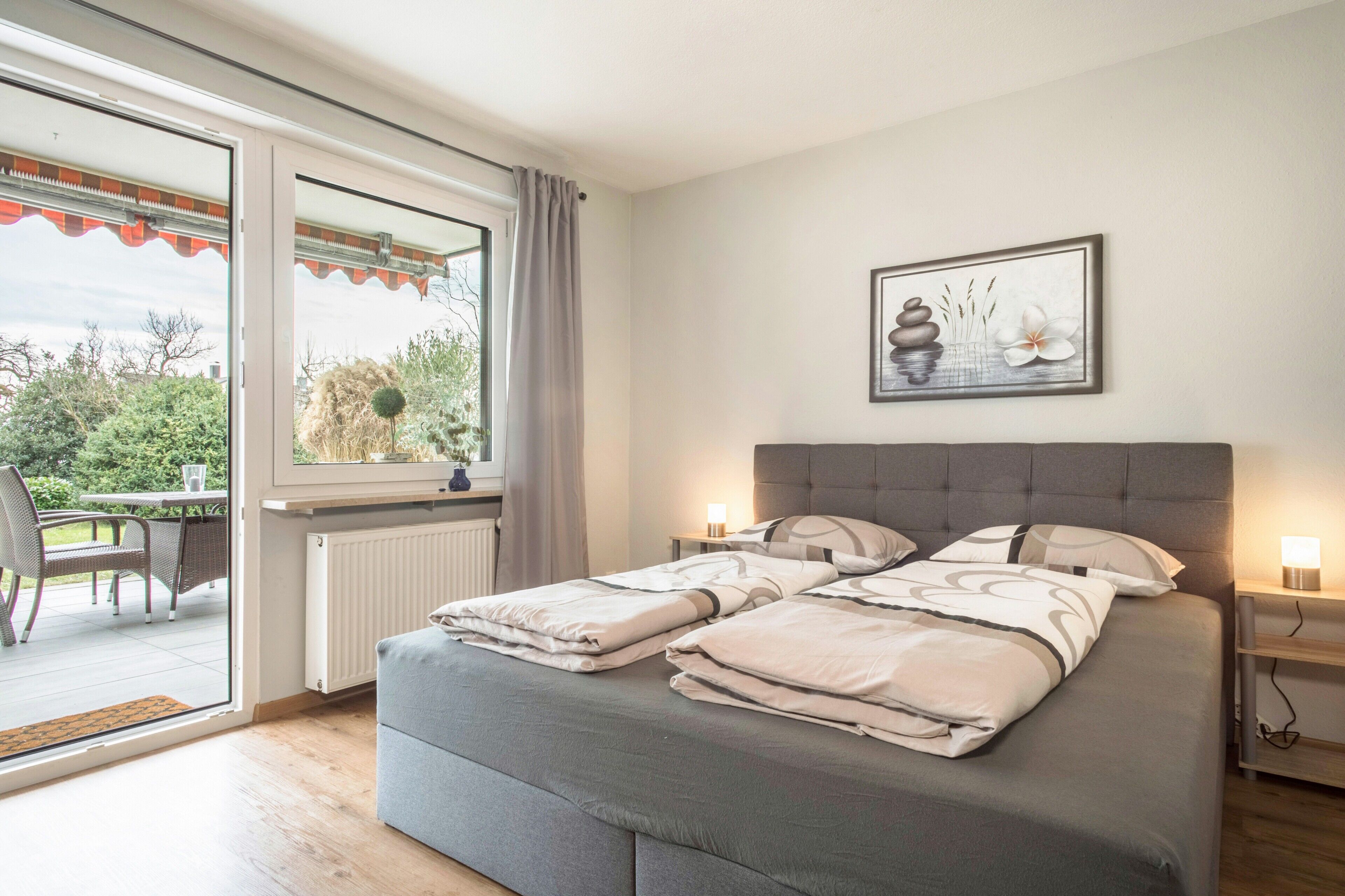 Ein Schlafzimmer mit Bett, Nachttischen, einem Fenster und Blick ins Freie.