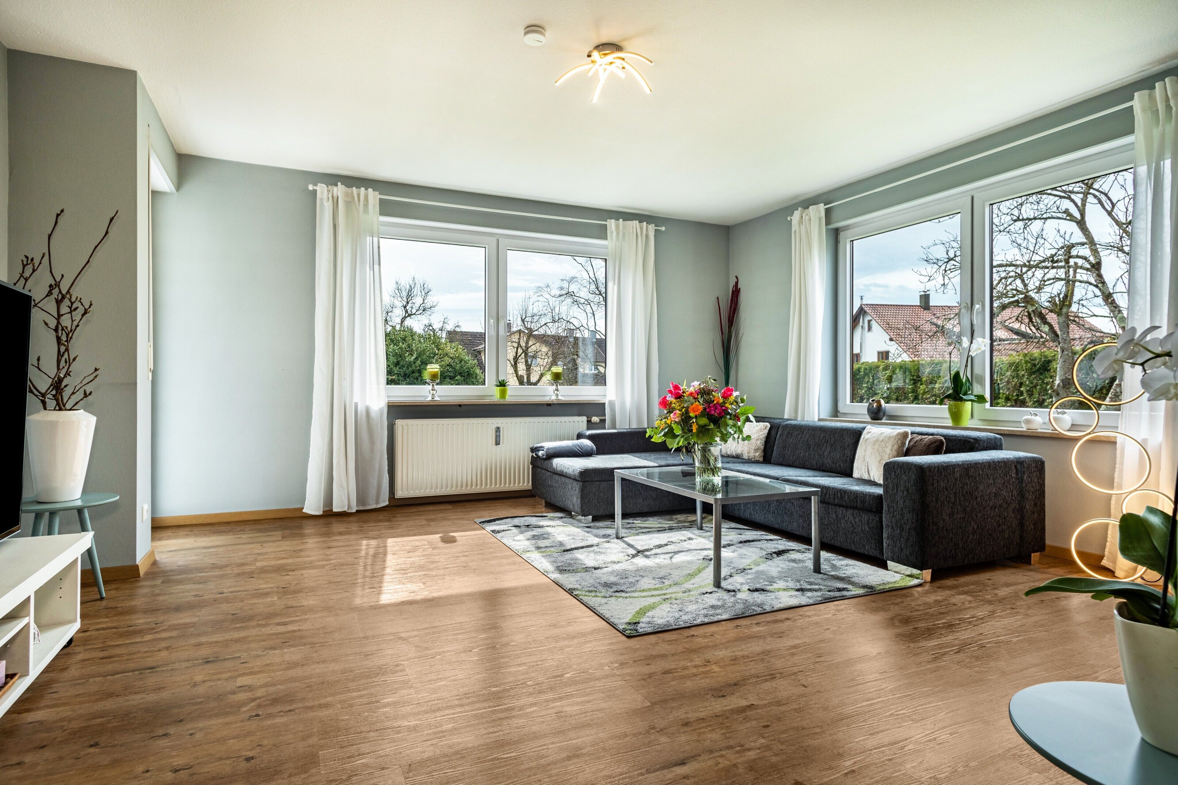 A modern living room with a sofa, coffee table, and large windows.
