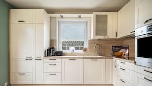 Eine moderne Küche mit weißen Schränken, einem Fenster, einer Kaffeemaschine und einem Backofen.