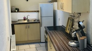 Uma cozinha compacta com geladeira, pia e cafeteira.