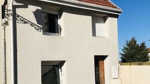 Um edifício de dois andares com telhado em telhas, uma janela pequena e uma porta.