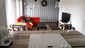 Ein modernes Wohnzimmer mit einem roten Sofa, einem Esstisch und einer Küchenzeile mit Herd.