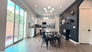 A modern kitchen with a dining area, large windows, and a chandelier.