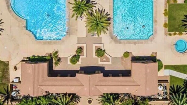 An aerial view of a resort with two large swimming pools, surrounded by palm trees and a covered walkway. - Luxury Gated Retreat – Resort Amenities, Pool, Spa, Gym (Mesa)