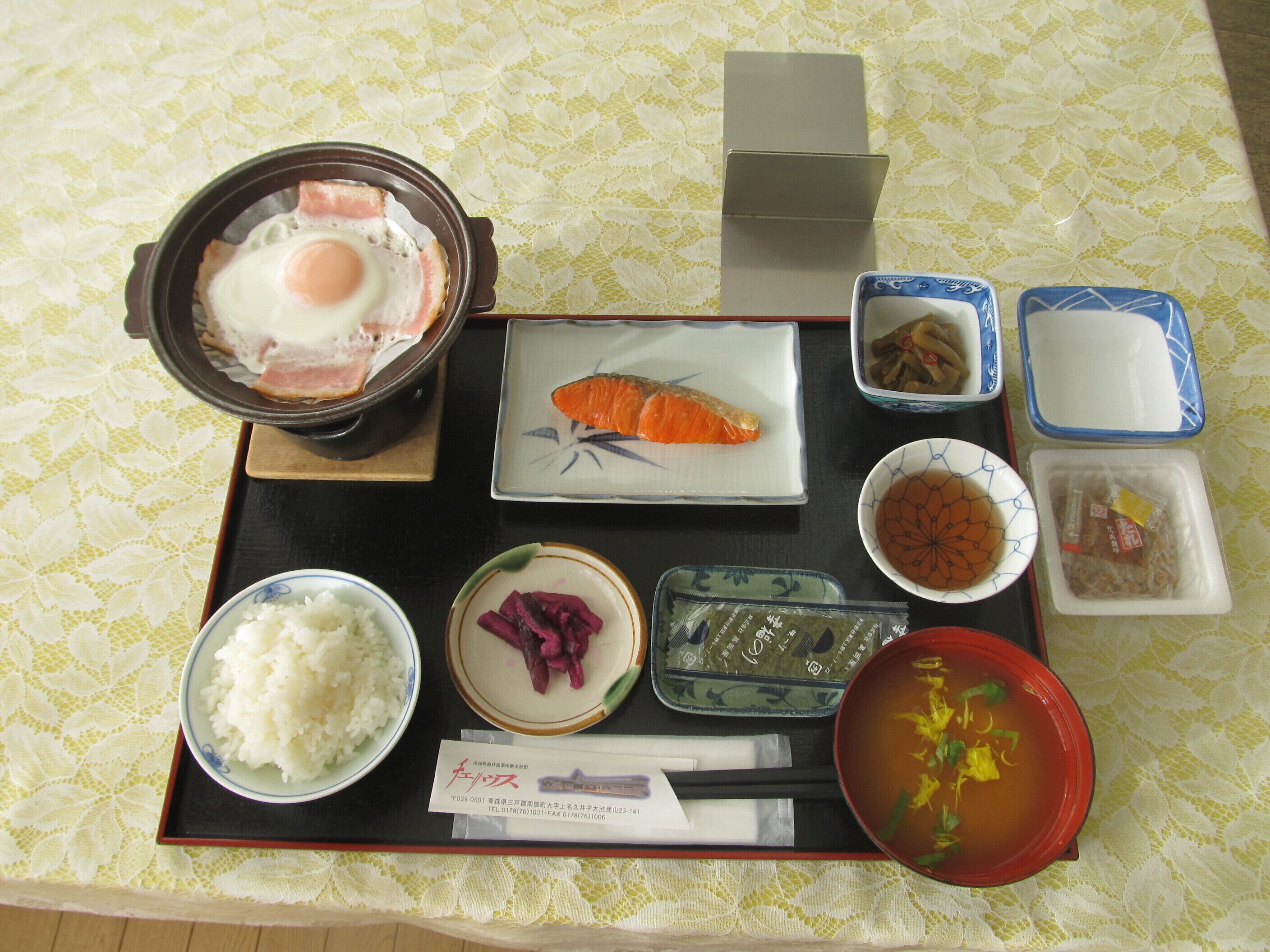 En bakke med forskellige japanske retter, herunder ris, laks og suppe.