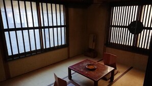 Ett traditionellt japanskt rum med tatamimattor på golvet, ett l ågt bord med en skål och shojiskärmar.