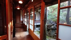 En traditionell träinredning med skjutdörrar som leder ut till en balkong med en stenmur och grönska utanför.