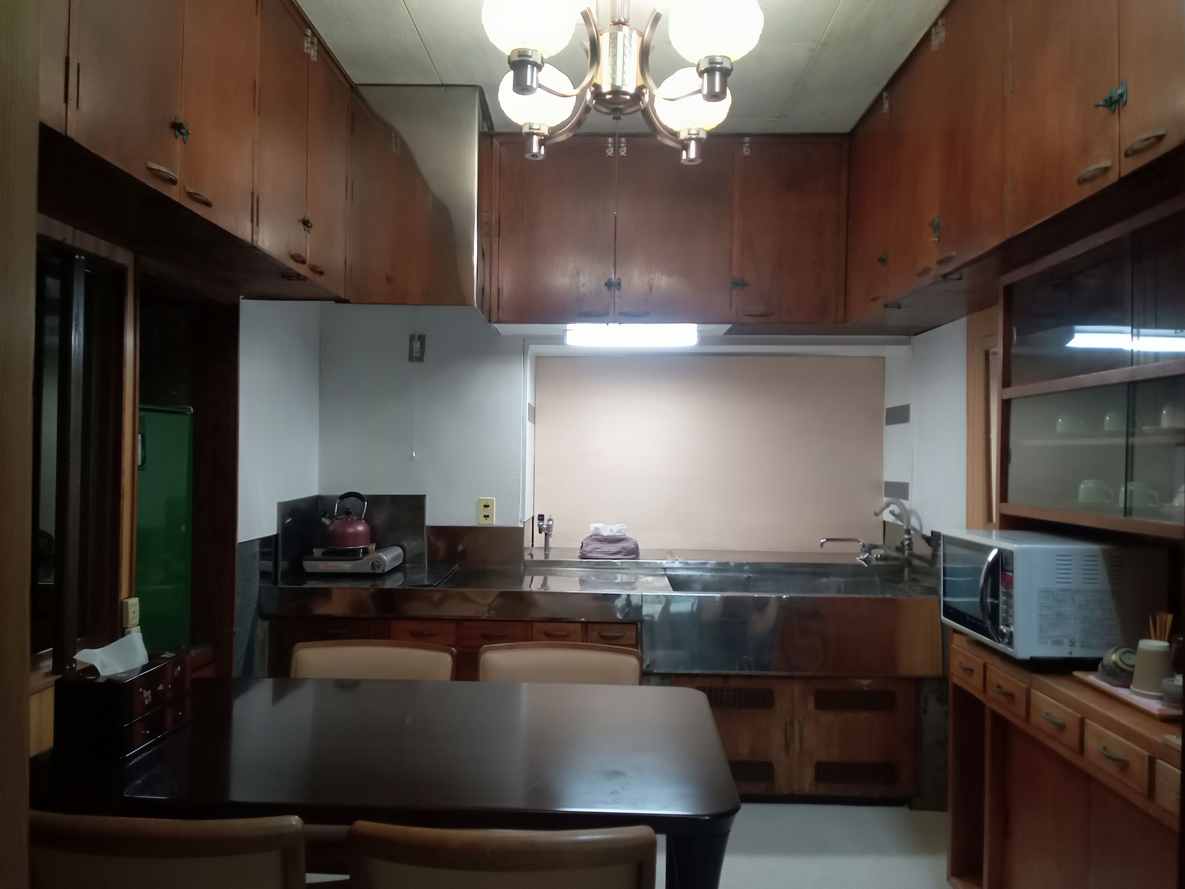 A kitchen with wooden cabinets, a dining table, and a built-in microwave.