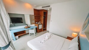 A hotel room with a bed, a desk, a television, and a wardrobe. - Natalie House Kata Beach (Karon)
