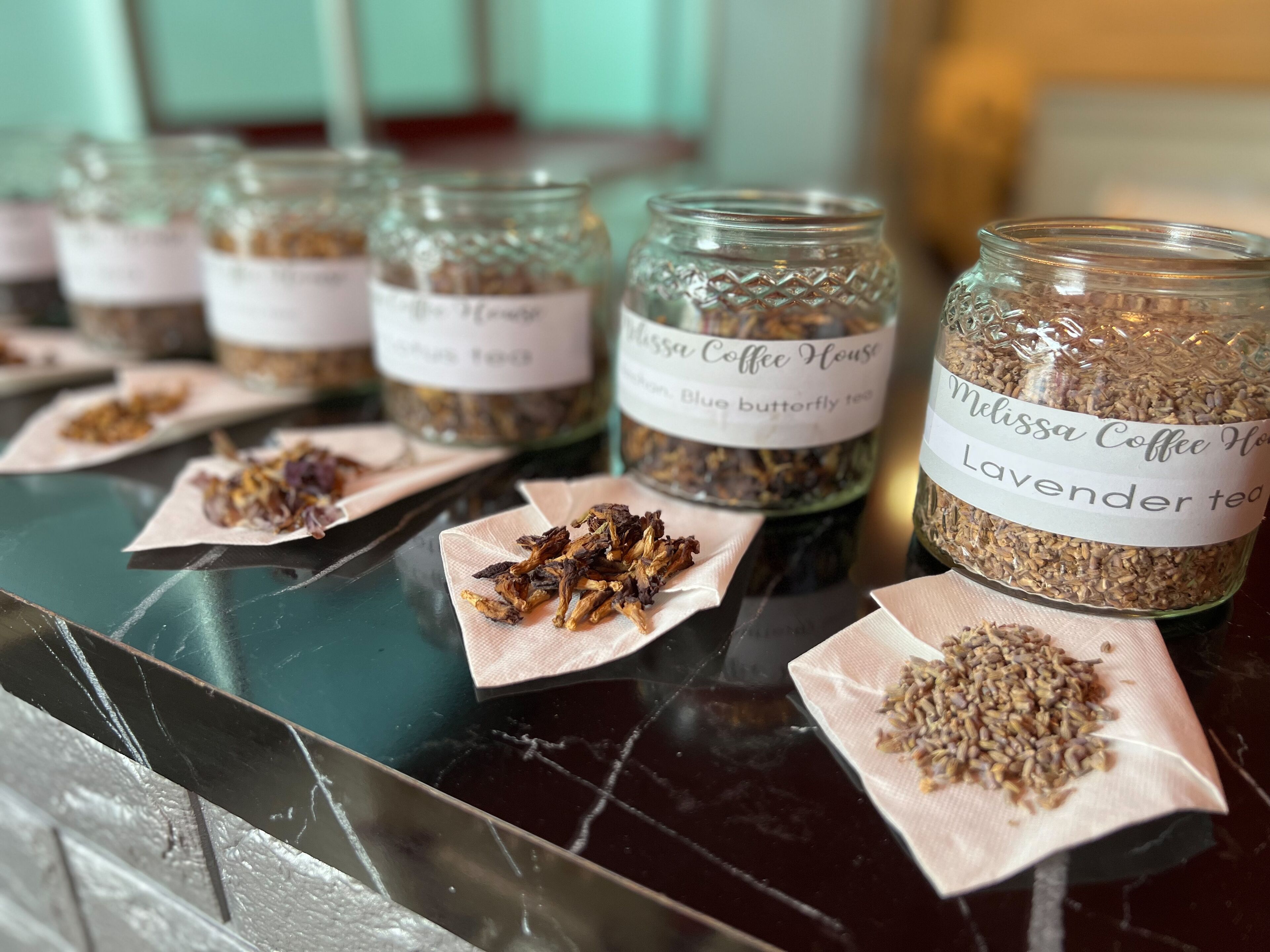 Several glass jars labeled with different types of tea on a table.