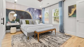 A modern bedroom with a bed, bedside table, bench, and a ceiling fan.