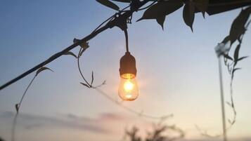 A hanging light bulb against a sunset sky.