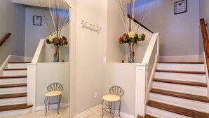 Eine Treppe mit Holzstufen und weißen Geländern, zwei Metallstühle und zwei Vasen mit Blumen.