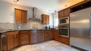 Eine moderne Küche mit Holzschränken, einem Edelstahlkühlschrank, einer Mikrowelle und einem Backofen.