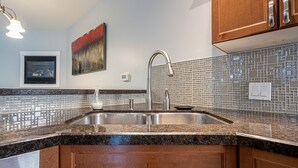 Eine Küche mit Granit Arbeitsplatten, Spüle aus Edelstahl und Holzschränken.