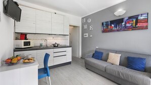 Et moderne køkken med hvide skabe, en mikrobølgeovn og et spiseområde med en blå stol.