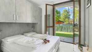 Et soveværelse med to senge, en skydedør til en have og et moderne design.