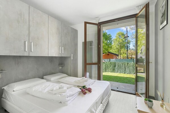 A bedroom with two beds, a sliding glass door to a garden, and a modern design.
