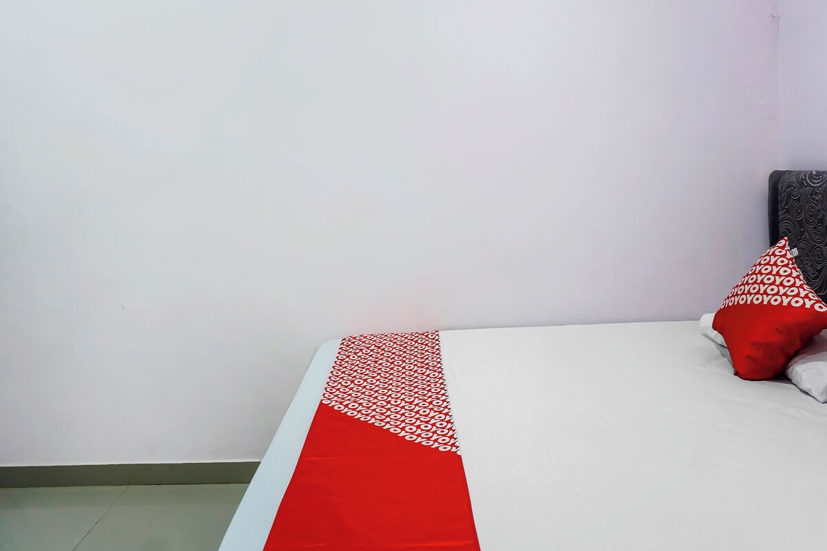 A bed with a red and white patterned bedspread, two red pillows, and a dark headboard.