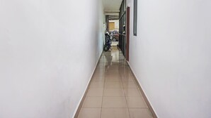 A narrow, tiled hallway with white walls and a motorcycle parked at the end. - Hotel O Homestay Madu Makassar (Makassar)