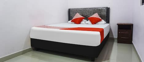 A neatly made bed with a white and red bedspread, two red and white pillows, and a dark headboard.