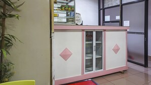 A kitchen area with a refrigerator, a cabinet with glass doors, and a shelf with food items. - Hotel O Homestay Madu Makassar (Makassar)