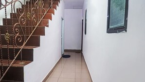 A narrow hallway with a staircase on the left, a pet door on the right, and a window on the far wall. - Hotel O Homestay Madu Makassar (Makassar)