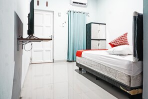 Ein Hotelzimmer mit Bett, Wandfernseher, Kleiderschrank und Vorhang.