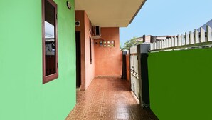 Un pasillo estrecho con una pared verde a un lado y una pared marrón al otro, que lleva a un portón.