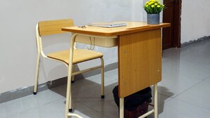 Un escritorio de madera con una silla, una libreta y una planta en maceta.