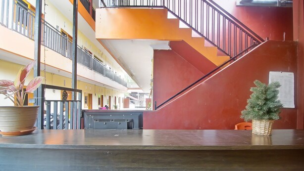 A multi-level interior with a staircase, a reception desk, and potted plants. - Hotel O A2b Guesthouse (Manado)