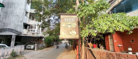 A street view with a sign for YAHVI HOTEL, featuring a contact number and email address.