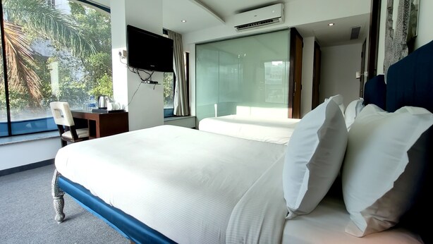 Een hotelkamer met een groot bed, een bureau met stoel, een televisie en een raam met uitzicht op groen.
