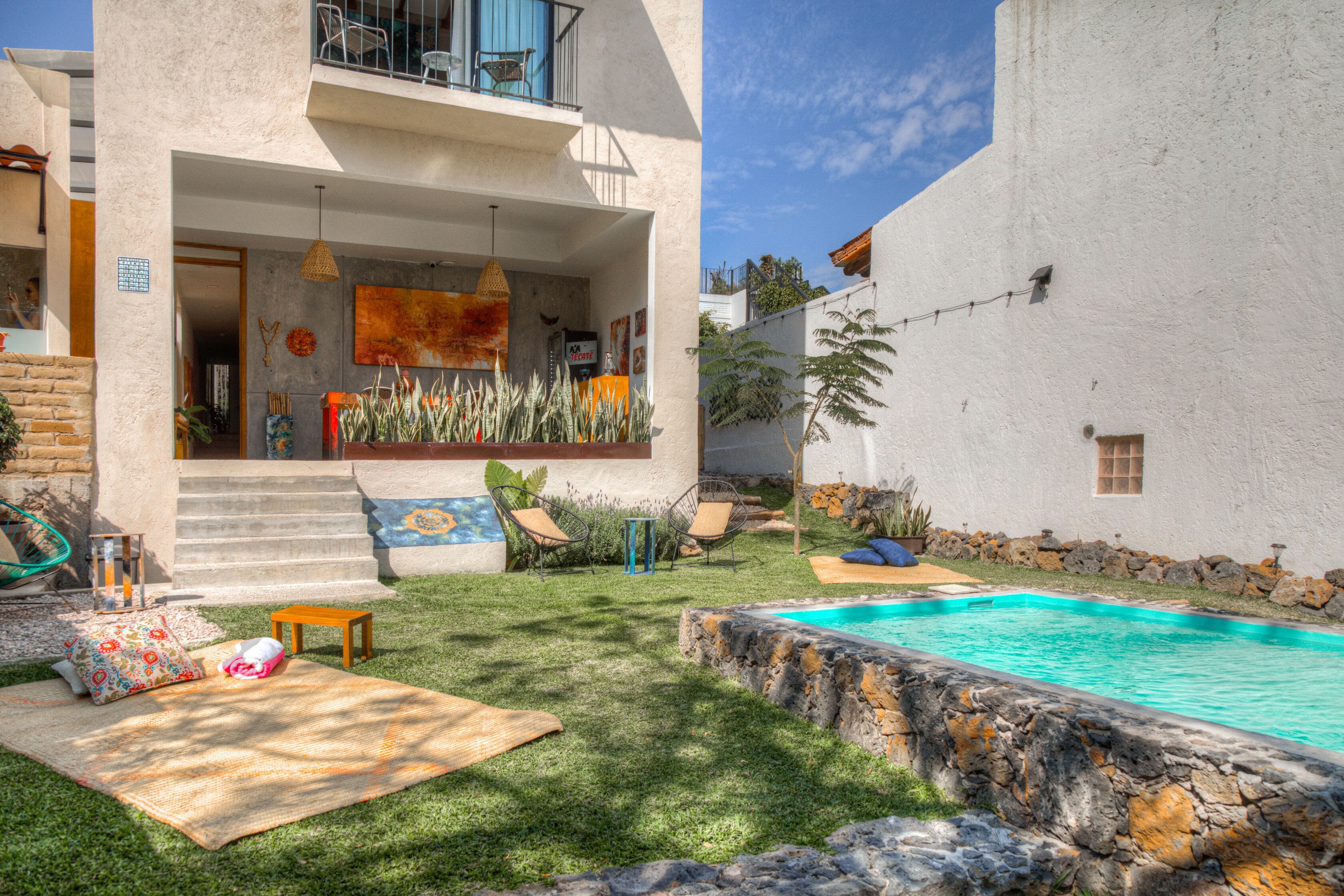 Una casa moderna con piscina, un porche cubierto y un muro de piedra.