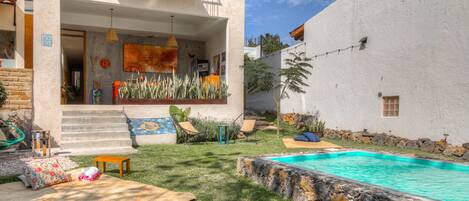 Una casa moderna con piscina, un porche cubierto y un muro de piedra.