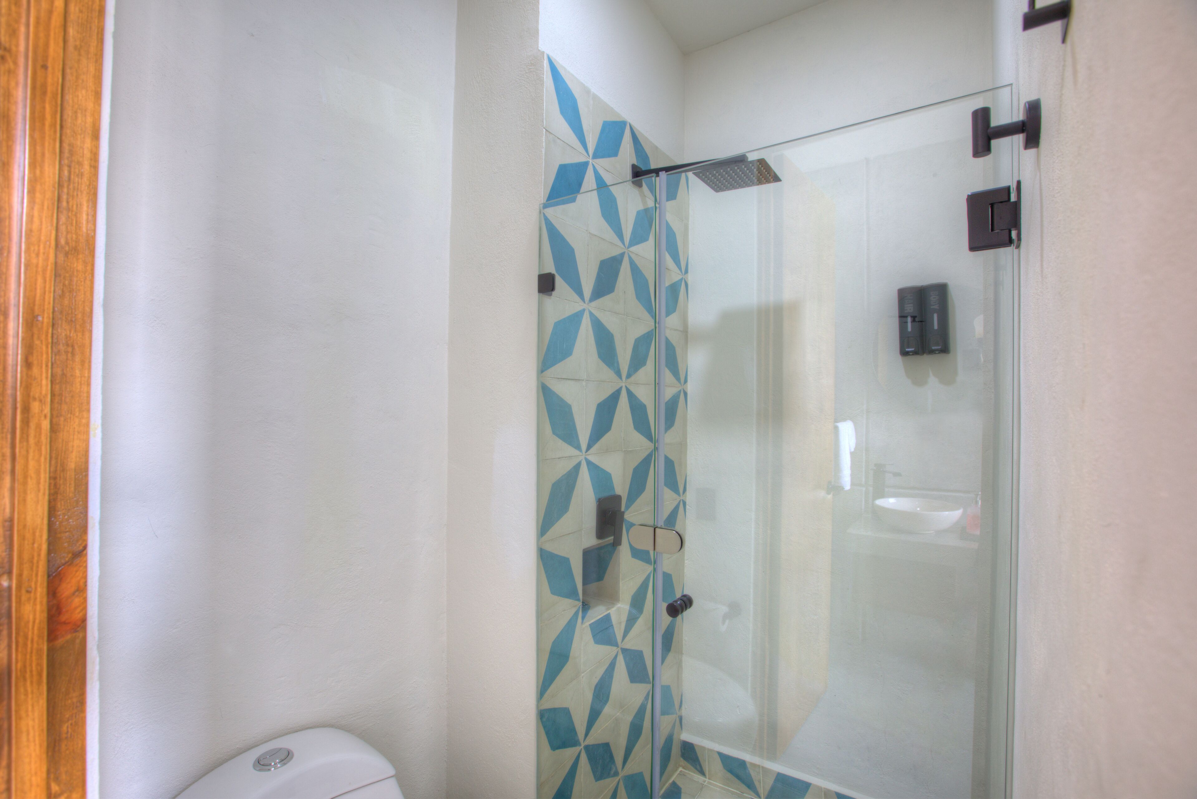 Een badkamer met een douchecabine van glas, een toilet en een wastafel.